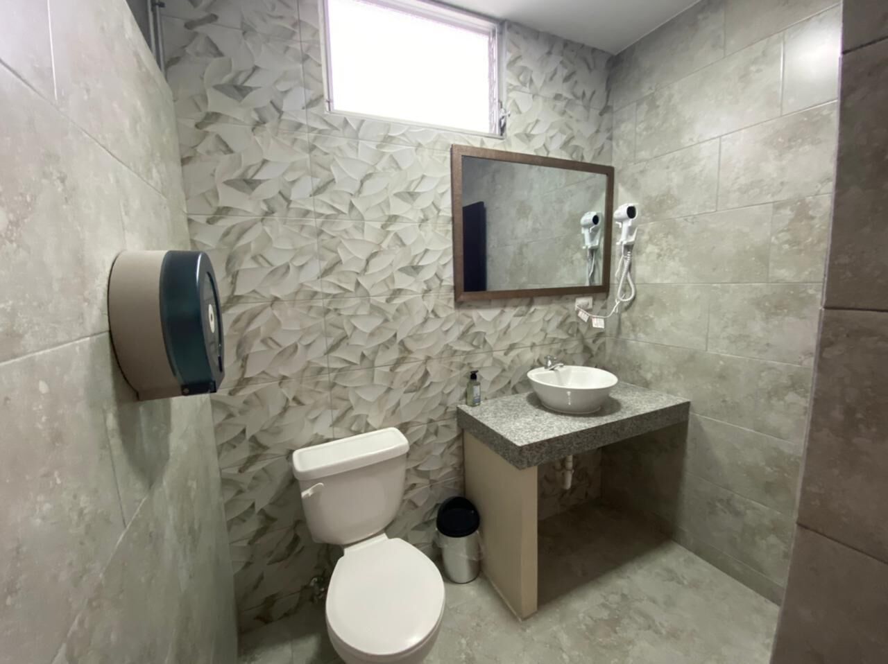 A bathroom with a toilet, sink, and mirror.