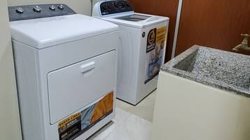 A laundry room with a washing machine, dryer, and a wooden wardrobe.