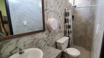 Un baño con lavamanos, inodoro y ducha.