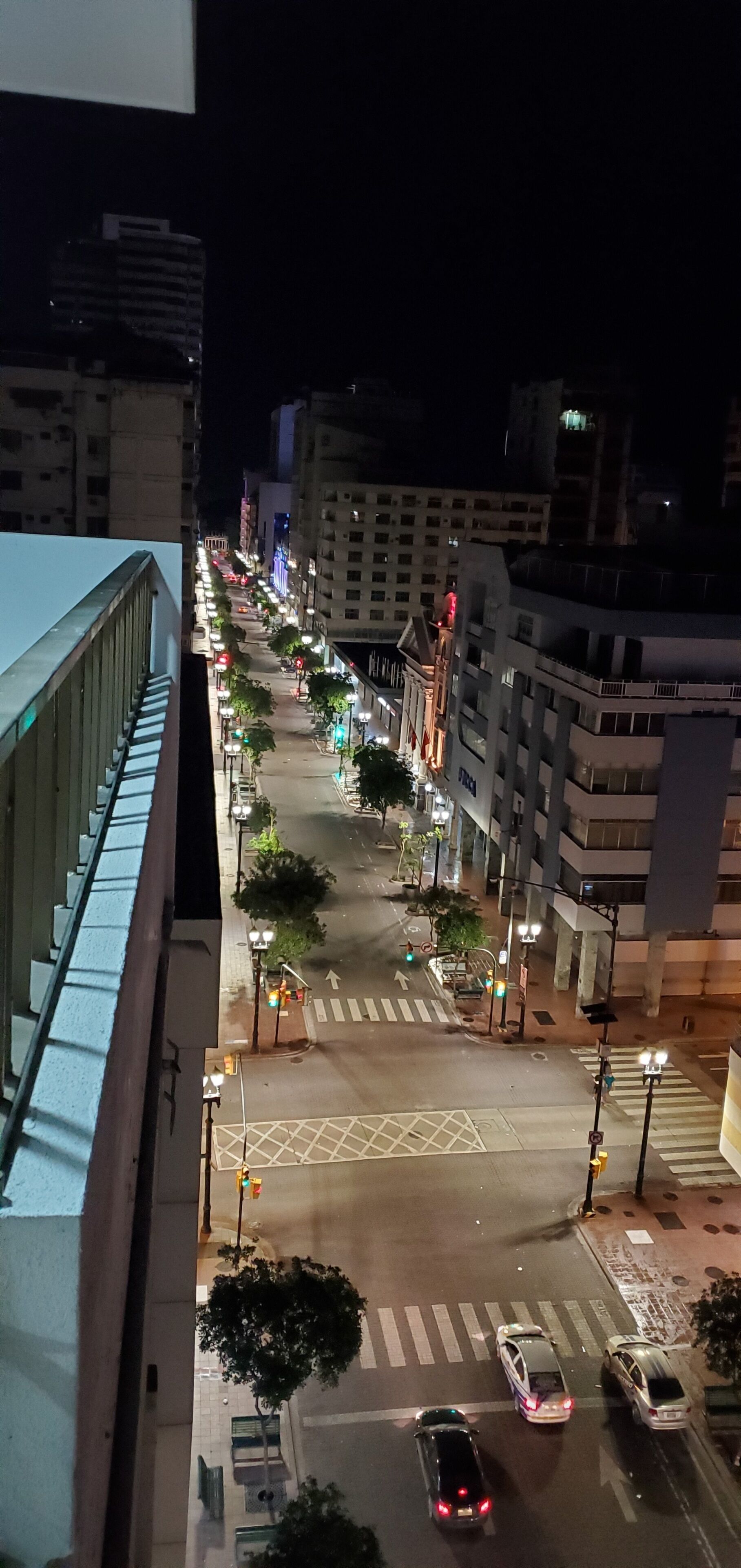 Una calle urbana iluminada con edificios, farolas y automóviles.