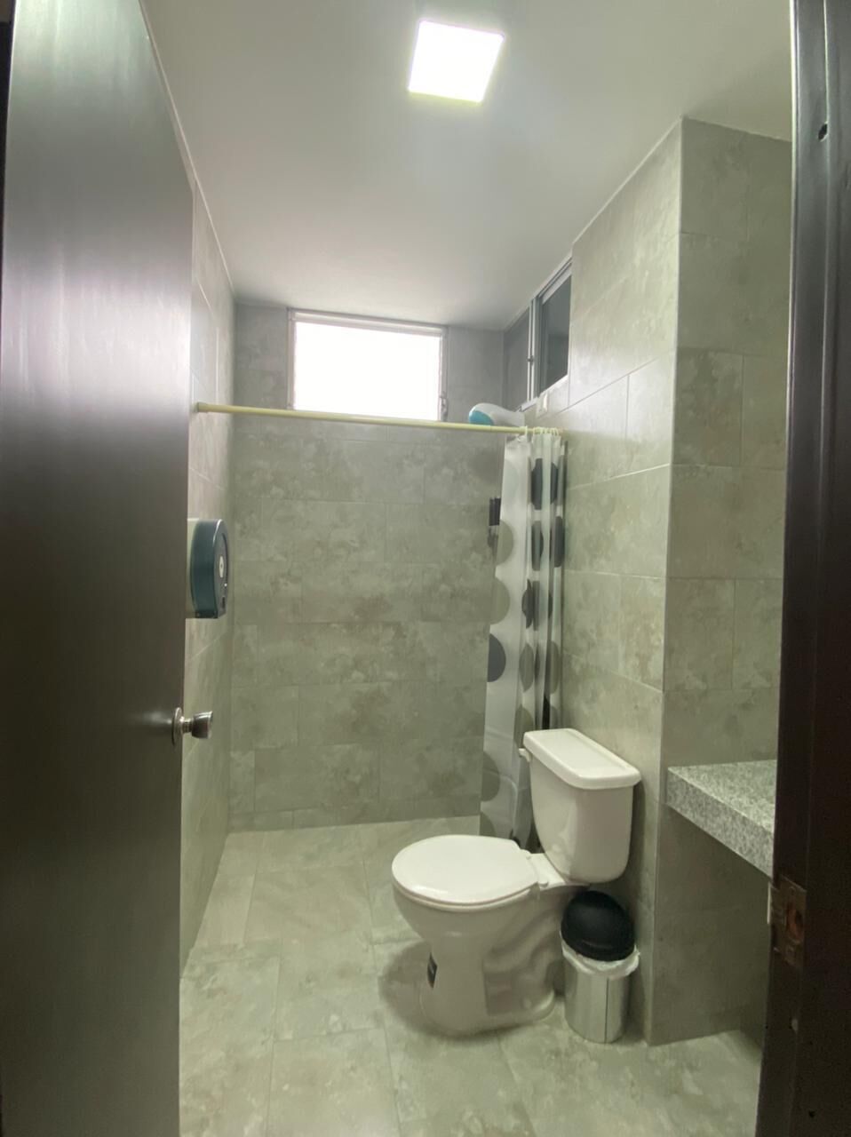 Een badkamer met een toilet, douchegordijn en een prullenbak.