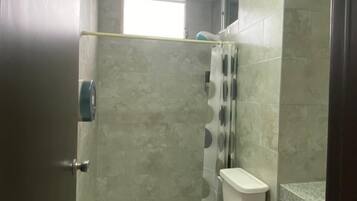 Een badkamer met een toilet, douchegordijn en een prullenbak.