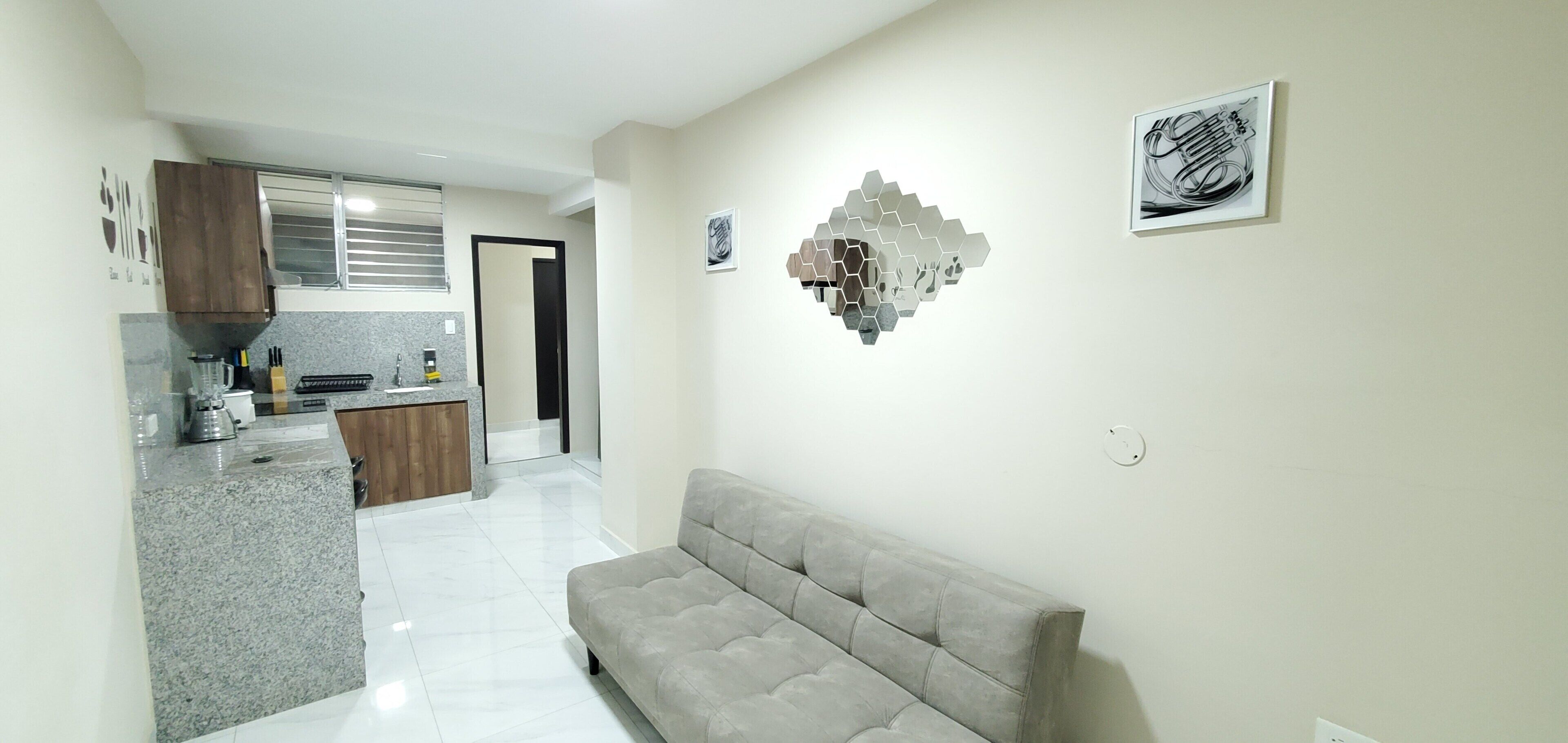 A modern kitchen with granite countertops, a built-in oven, and a dining area with a grey sofa.