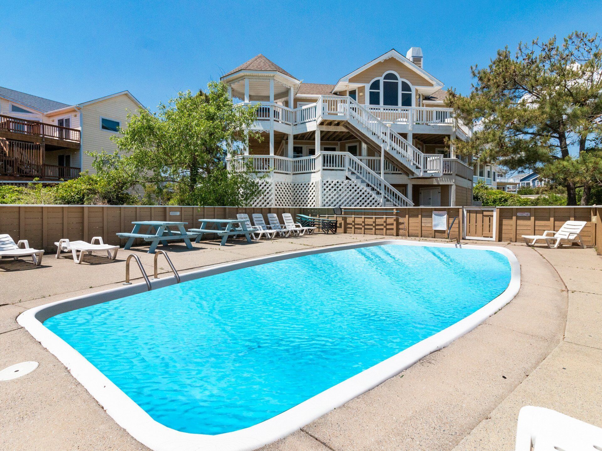 A swimming pool with lounge chairs and a building with a balcony in the background.