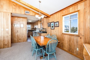 Un intérieur en bois comprenant une table et des chaises, un coin cuisine et des tableaux encadrés accrochés au mur.