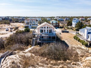 Un quartier résidentiel situé sur la côte, composé de plusieurs maisons, dont une grande maison à deux étages dotée d’un balcon et d’un escalier menant à une terrasse.