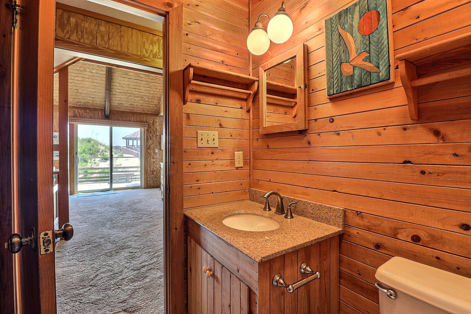 Een houten badkamer met een wastafel, badkamermeubel en toilet.