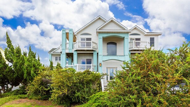 A large, two-story house with multiple balconies and a prominent front porch. - Fun in the Sun: Pool, Hot Tub & Beach (Corolla)