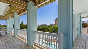 A wooden deck with a pool, white railings, and a clear view of houses in the background. - Fun in the Sun: Pool, Hot Tub & Beach (Corolla)