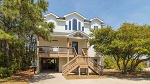 A two-story building with a porch and a staircase leading to the entrance. - It's 5 O'Clock Somewhere – Beach,  Pool & Hot Tub (Corolla)