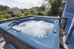 A hot tub on a wooden deck with a view of residential buildings in the background.