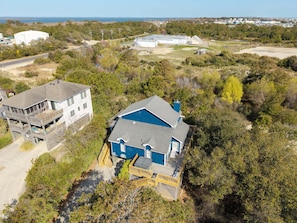 Vue aérienne d’une propriété située sur la côte, comprenant une grande maison, un bâtiment plus petit et un grand réservoir de stockage.