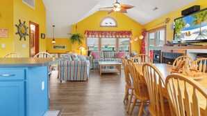 Una cocina luminosa con armarios de madera, una zona de comedor con sillas a rayas y un ventanal con vistas al exterior.