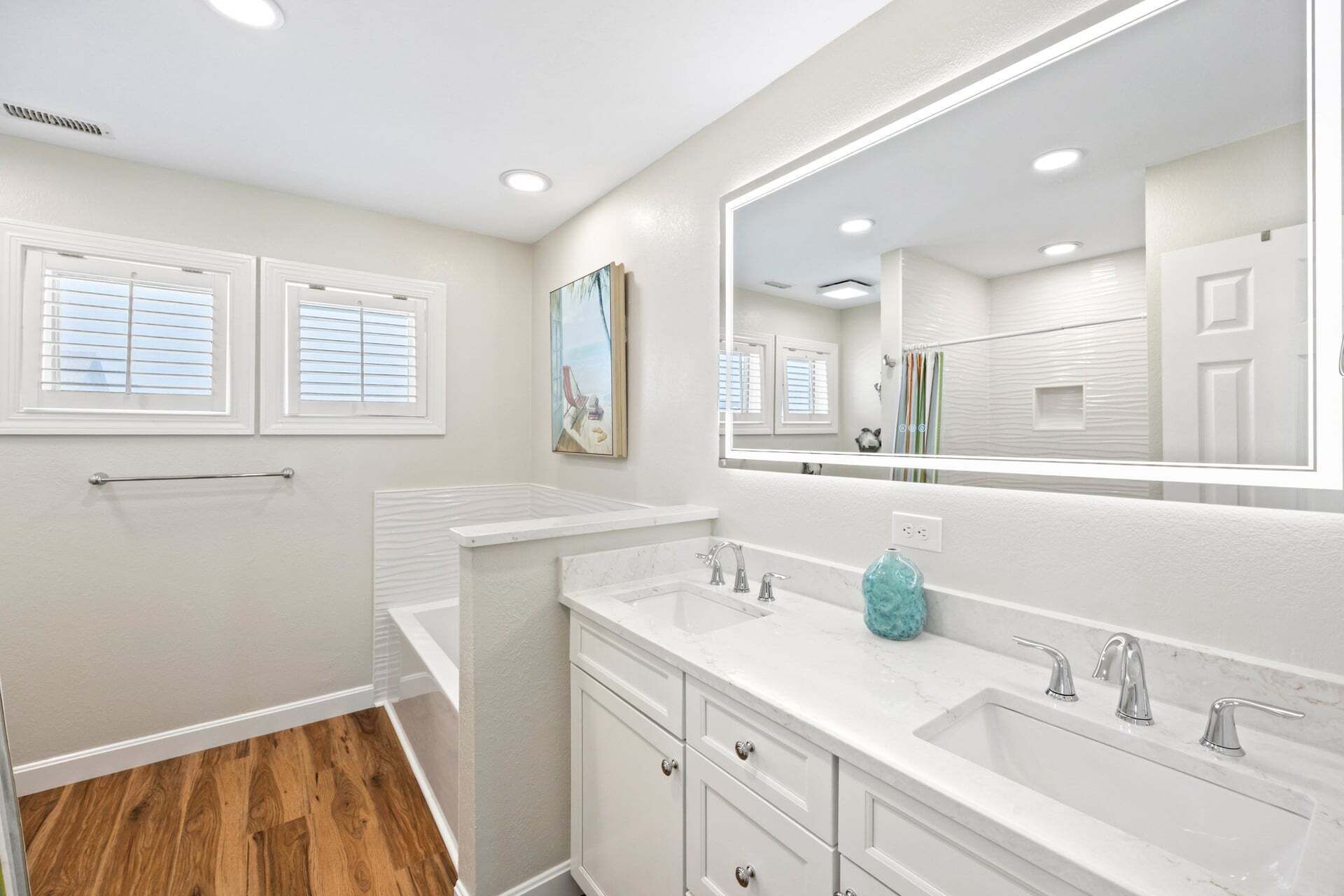 A bathroom with two sinks, a large mirror, and a window with blinds.