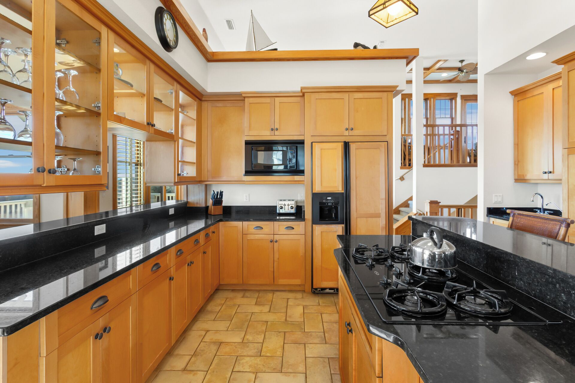 A modern kitchen with wooden cabinets, a black countertop, and a gas stove.