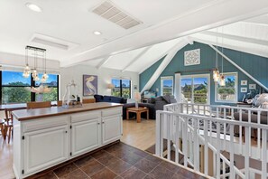 A spacious living area with a large kitchen, a dining table, and a balcony with a white railing.