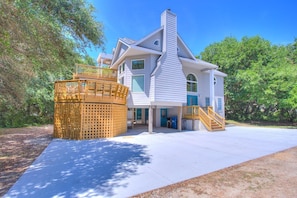 A two-story house with a large deck and a staircase leading to the second floor.
