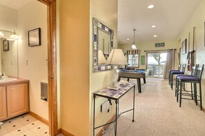 A hotel room with a bathroom, a pool table, and a seating area with chairs.