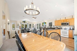 Een ruime keuken met houten kastjes, een groot eiland en een eethoek met een houten tafel en stoelen.