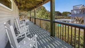 A wooden deck with white chairs, a pool, and a view of trees and a building. - Merryweather: Pool, Hot Tub, Ocean + Sound Access (Duck)