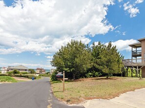 A residential street with houses, a large tree, and a clear sky. - Horizon's Summit: Ocean Views, 2-Min Walk Beach (Duck)