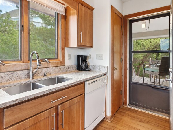 A kitchen with wooden cabinets, a stainless steel sink, and a coffee maker. - Horizon's Summit: Ocean Views, 2-Min Walk Beach (Duck)
