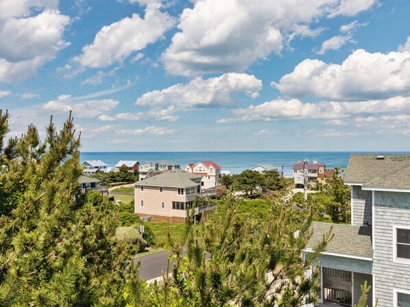 A coastal residential area with houses, a clear sky, and the ocean in the background. - Horizon's Summit: Ocean Views, 2-Min Walk Beach (Duck)
