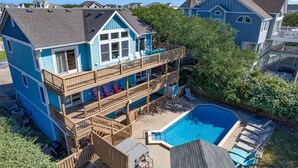 A two-story house with a balcony, a swimming pool, and a deck area. - Sol Mates: Pool, Tiki Bar, 3-Min Walk Beach OBX (Duck)