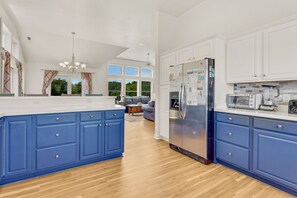 A modern kitchen with blue cabinets, a stainless steel refrigerator, and a built-in oven.