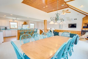 A spacious kitchen with white cabinets, a wooden dining table, and blue chairs.