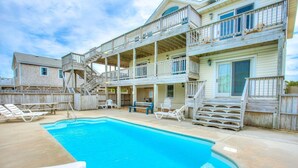 A two-story building with a swimming pool, outdoor seating, and a wooden deck. - Morning View: Ocean Views, Pool, Hot Tub, Game Room (Southern Shores)