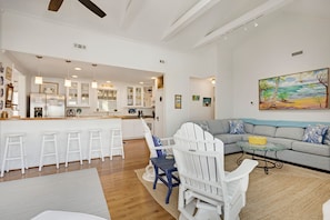 A spacious living area with a grey sofa, a small round table, and a white Adirondack chair.