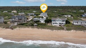 Ein Küstenwohngebiet mit Häusern an einem Hang, einem Strand im Vordergrund und einem Leuchtturm als Sehenswürdigkeit.