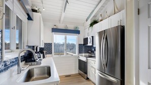 A modern kitchen with a stainless steel refrigerator, a built-in oven, and a coffee maker.
