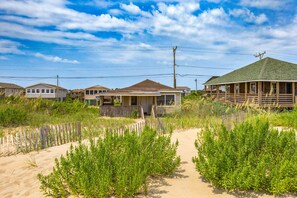 A beachfront property with multiple houses, a sandy path, and vegetation. - Neaptide: Oceanfront Escape for Two w/ Deck Views (Kitty Hawk)