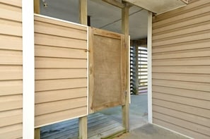A wooden door with a metal latch, a concrete floor, and a wooden fence in the background.