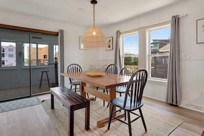 Een eetgedeelte met een houten tafel, stoelen, een bank en een hanglamp.
