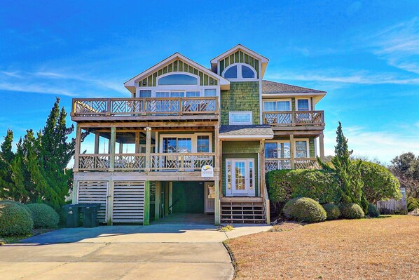A two-story house with a balcony, a garage, and a well-maintained lawn.