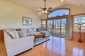 A spacious living room with a large sofa, a coffee table, and a ceiling fan.