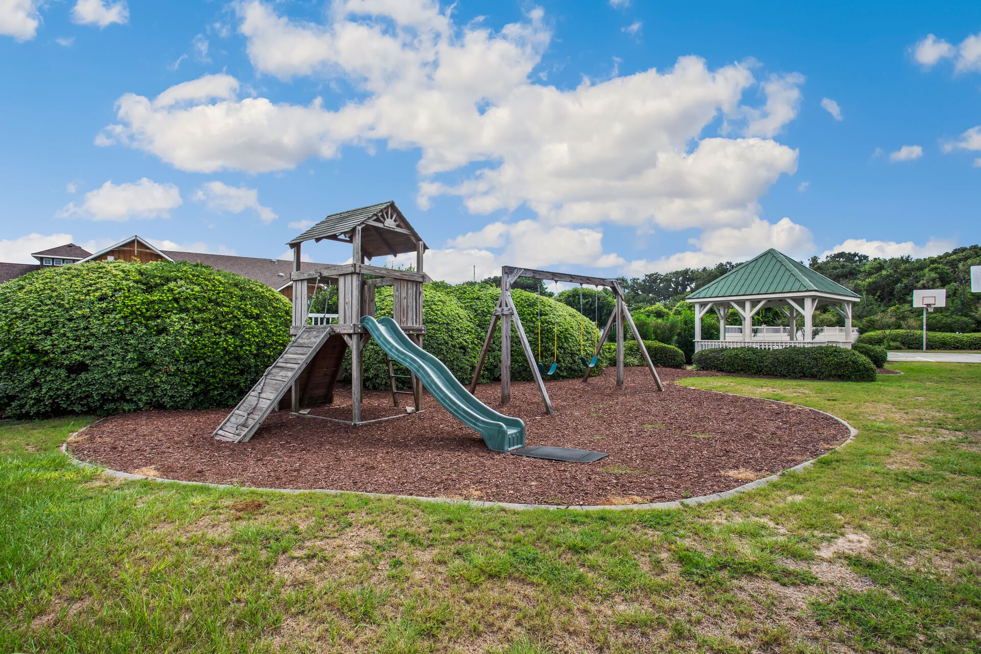 A playground with a slide, swings, and a gazebo.