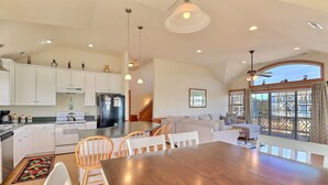 A spacious kitchen with white cabinets, a large island, and a dining area with wooden chairs. - Sound Side Out: Family Home w/ Pool & Amenities (Kitty Hawk)