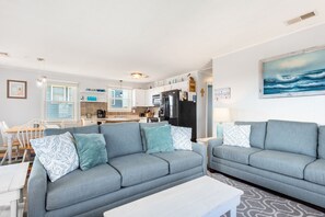 Relax in this stylish living room with two sofas, a coffee table, and a large window offering a view of the adjacent kitchen.