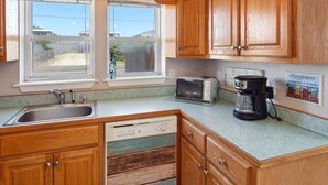 A kitchen with wooden cabinets, a stainless steel sink, a dishwasher, a toaster, and a coffee maker. - Flip Flop Inn * No Stairs * Close to Beach (Kill Devil Hills)