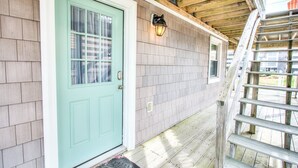 A house with a light blue front door, a wooden porch, and a wooden staircase.