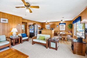 A compact living space with a kitchenette, a dining area, and a seating area with a sofa and chairs. - Timeless OBX Charm | Steps to the Beach (Kill Devil Hills)