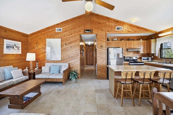 A cozy cabin interior with a living area, kitchen, and dining space.