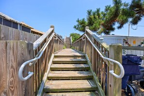 A wooden staircase leading to a building with a thatched roof.