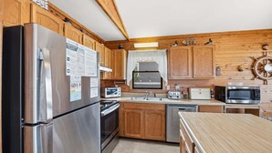 A compact kitchen with wooden cabinets, a stainless steel refrigerator, a microwave, a toaster, and a sink. - 5215 Edwards * 3 Min Walk to Beach (Kill Devil Hills)