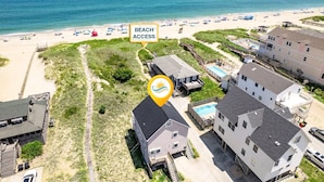 Une propriété située en bord de mer, dotée d’une piscine, d’un accès direct à la plage et d’une promenade en bois menant à la plage.