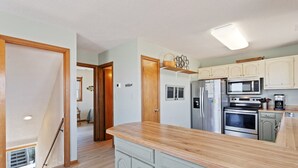 Une cuisine avec des meubles en bois, un réfrigérateur en acier inoxydable, un four à micro-ondes et un four traditionnel.
